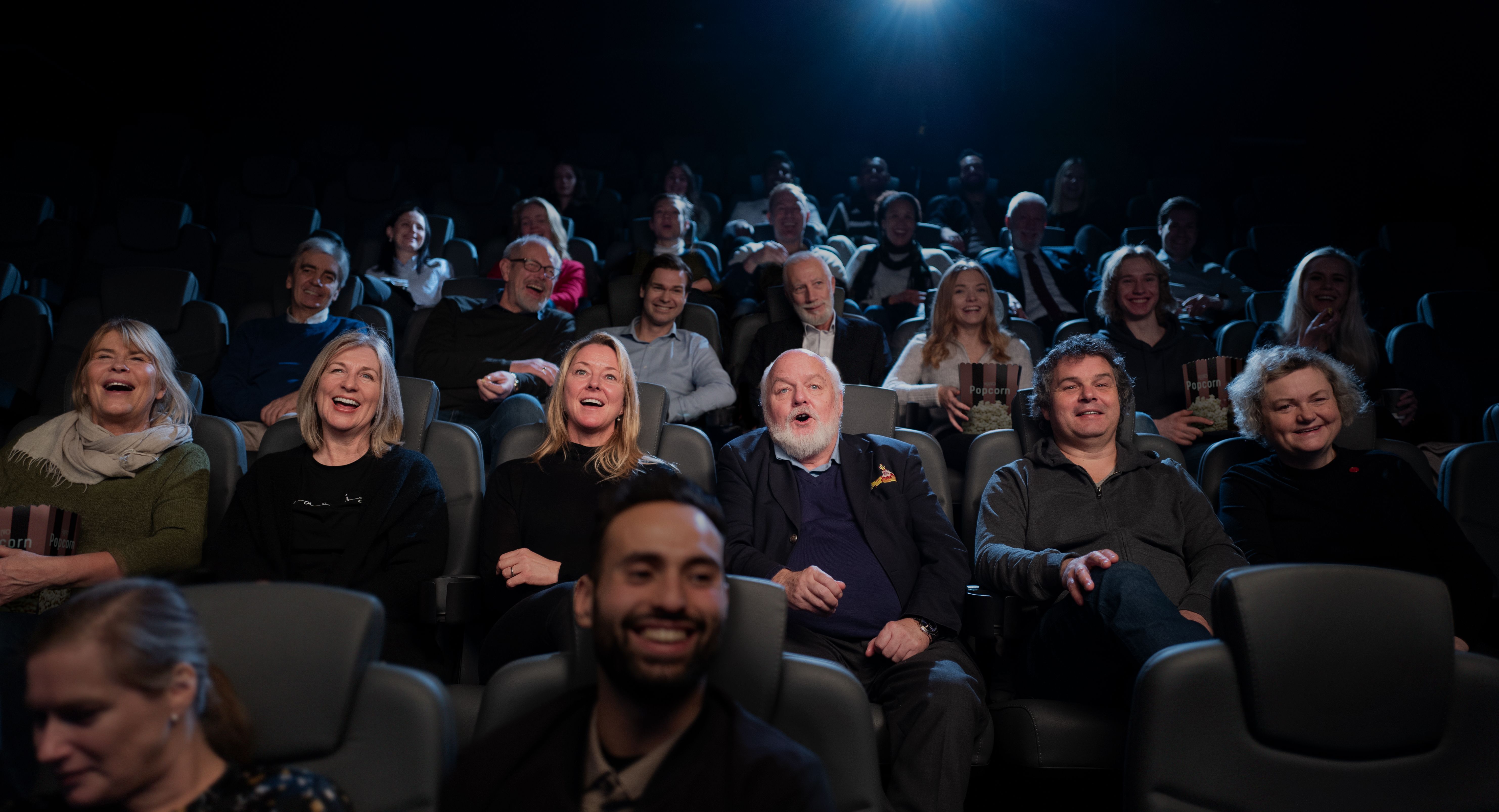 Personer i mørk kinosal som ser på film