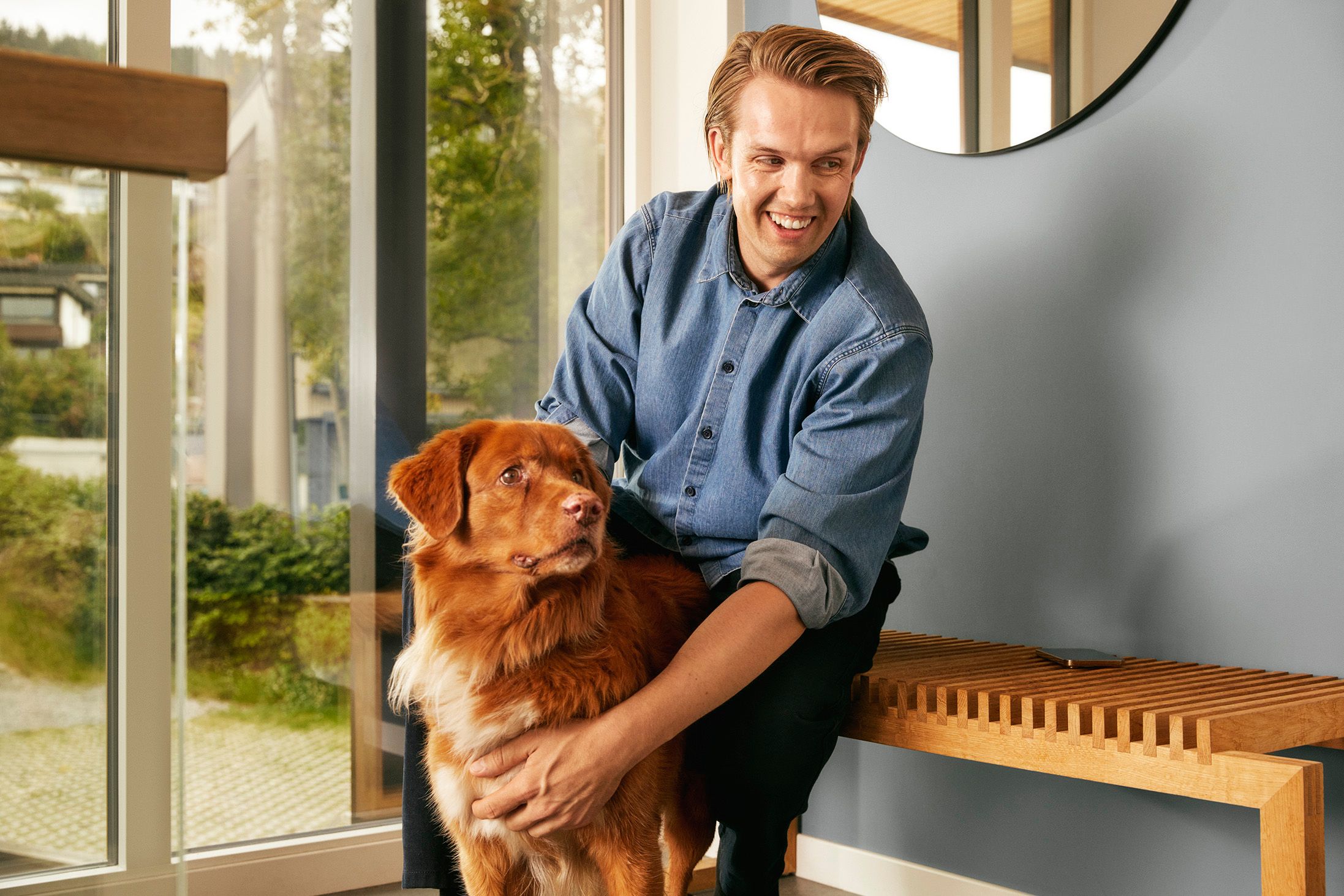 mann sitter i gangen og koser med hund