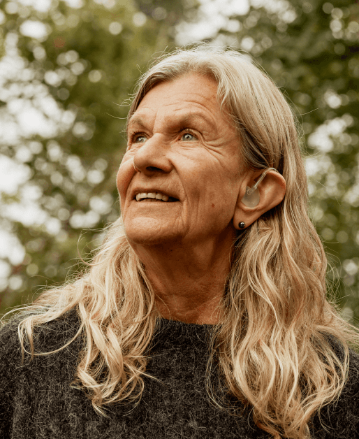 Voksen kvinne med høreapparat ser utover