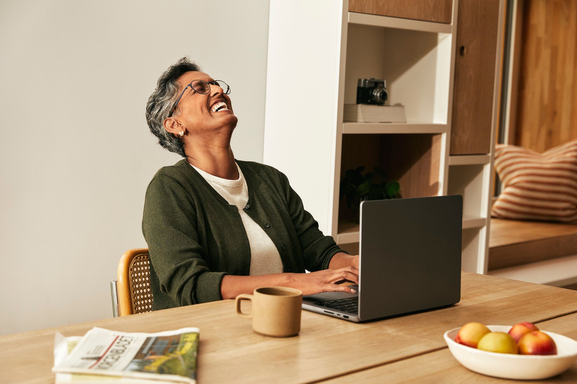 Dame som smiler og ler og skriver på laptop